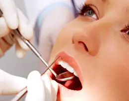 Um dentista inspecionando os dentes de alguém com um espelho dental